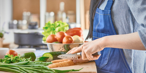 A young woman prepares food in the kitchen. Healthy food - vege