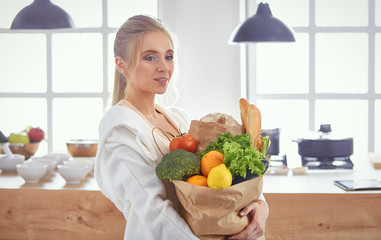 Young woman holding grocery shopping bag with vegetables Standi