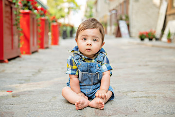 Fototapeta premium Portrait handsome baby boy sitting on stone street