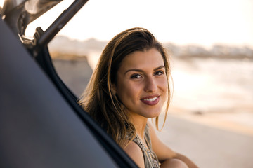 Fototapeta na wymiar Girl near the beach sitting on the car