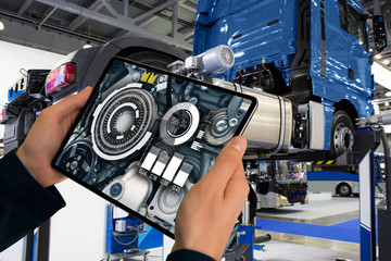 Serviceman repairing a truck using augmented reality application.	