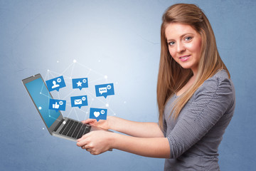 Woman holding laptop with different types of social media symbols and icons