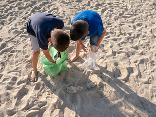 two young boys collecting rubbish and plastic on the beach