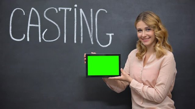 Girl offering online registration for casting, holding tablet with green screen