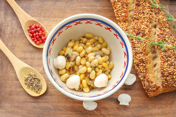 Bowl with tasty boiled legumes on wooden board