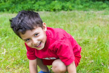 cheerful boy sitting on the grass in the summer