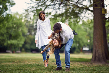 Fototapeta premium smiling family playing and spinning in park