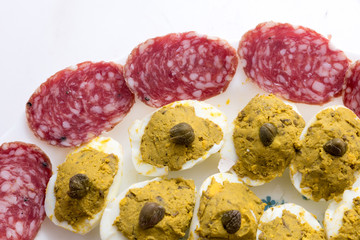 Appetizer with stuffed eggs and sliced salami