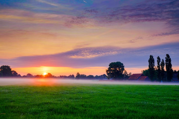 Obraz na płótnie Canvas Colorful glowing sunrise over a countryside farming area, creating an idyllic scenic landscape