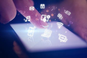 Finger touching phone with hologram application icons and dark background