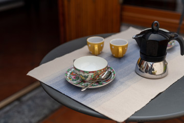 a set of decorated coffee cups with coffemaker, on a table set for breakfast, interior design on a balcony