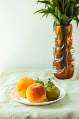 Still life with fresh peaches and plums on linen cloth background on wooden table. Bright juicy summer fruits.