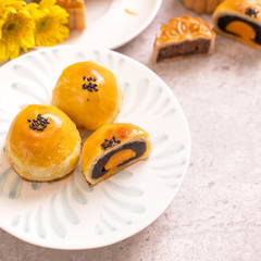 Mid-Autumn Festival traditional food concept - Beautiful cut moon cake on blue pattern plate on white background with flower, close up, copy space