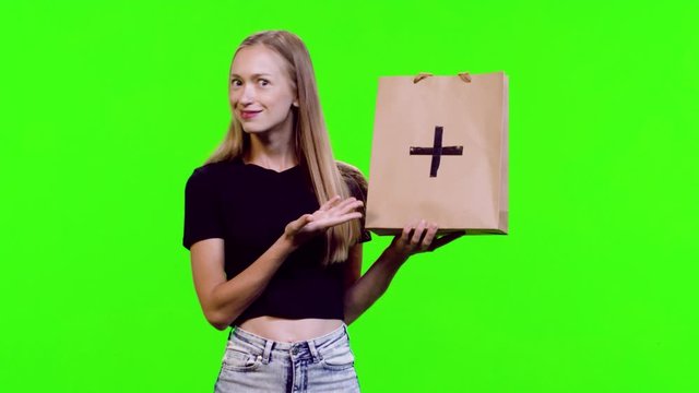 Beautiful model lifting and presenting a shopping bag (with a marker), reacts happily and cheerfully, over green screen. Use marker for logo placement. 3 takes.