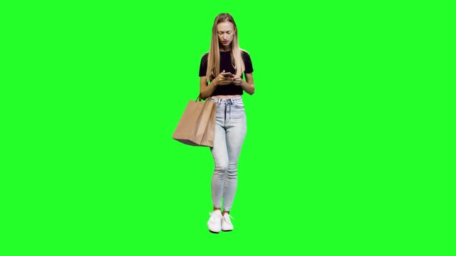 Taking a Selfie or using an app while walking, a beautiful woman with shopping bags over green screen.