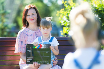 A little girl in headphones with a camera shoots the plot. Child blogger shoots mom and sister on...