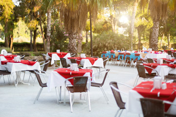 Laid tables for holiday on the street. The outdoor restaurant festively decorated with tables and chairs.