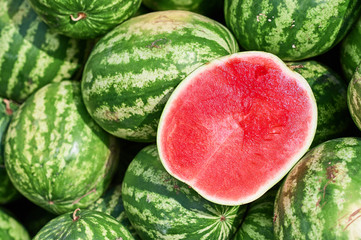 View from above at the large ripe and sweet watermelons that lie outdoors. One cut watermelon in half pitted.