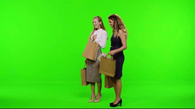 Window shopping, two fashionable female friends over green screen. Getting to a window, looking, and entering. 3 takes.