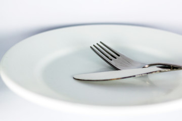 White empty plate with fork and knife 