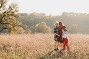 Samesex caucasian lesbian family with a child and a dog walking outdoors on the background of beautiful nature. Mothers having fun with their son.