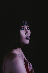 Weird woman with dark tone makeup on black background, portrait photograph
