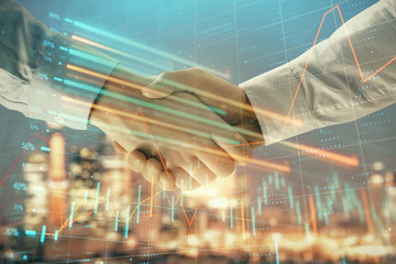 Double exposure of financial chart on cityscape background with two businessmen handshake. Concept of financial analysis and investment opportunities