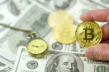hand hold bitcoin over the dollar bills with pocket watch