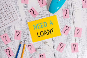 Writing note showing Need A Loan Question. Business concept for asking he need money expected paid back with interest Writing tools and scribbled paper on top of the wooden table