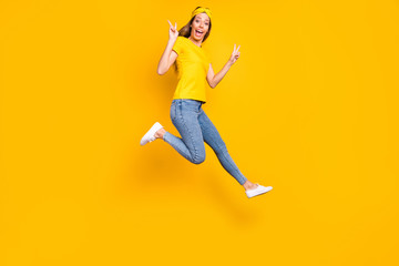Fototapeta na wymiar Full length photo of beautiful lady jumping high showing v-sign symbol wear casual clothes isolated yellow background