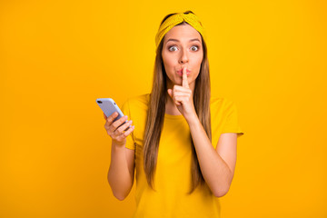 Naklejka premium Ładna pani trzymająca się za ręce telefonu, mówiąca w tajemnicy o niskich cenach, nosi casualową koszulkę na białym tle żółtym tle