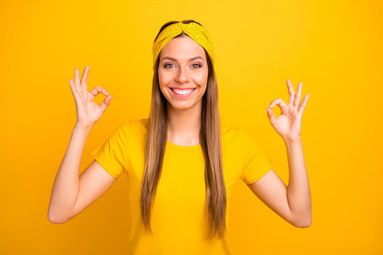 Portrait of lovely millennial showing double okay sign with beaming amile isolated over yellow background