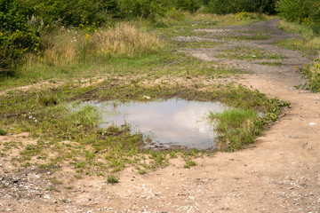 Large puddle on a dry dirt track