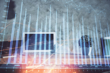 Double exposure of graph and financial info and work space with computer background. Concept of international online trading.