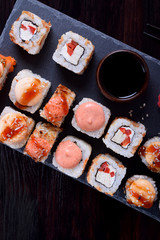 Sushi rolls assortment served on slate plate on black table