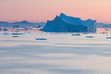 Arctic nature landscape with icebergs in Greenland icefjord with midnight sun sunset / sunrise in...