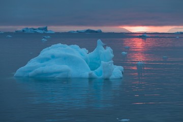 Arctic nature landscape with icebergs in Greenland icefjord with midnight sun sunset / sunrise in...