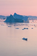 Arctic nature landscape with icebergs in Greenland icefjord with midnight sun sunset / sunrise in...