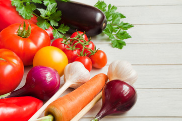 Tomatoes, peppers, eggplants and other vegetables on a white wooden table
