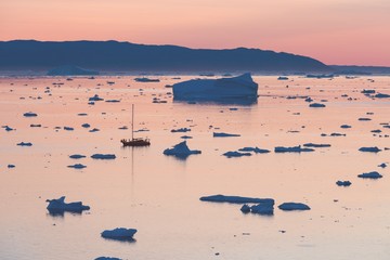 Arctic nature landscape with icebergs in Greenland icefjord with midnight sun sunset / sunrise in...