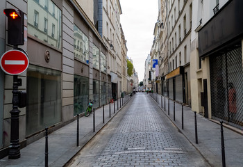 Paris narrow street stretching to the horizon. Beautiful facades of houses. Early morning, deserted. Traffic light and road sign. Parked bike and in a distance cars.