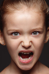 Close up portrait of little and emotional caucasian girl. Highly detail photoshot of female model with well-kept skin and bright facial expression. Concept of human emotions. Angry, agressive.