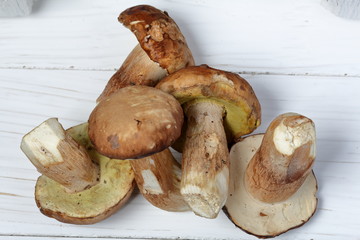 A few fresh porcini mushrooms on a background of white boards.
