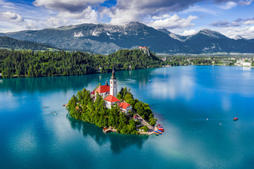 Bled, Slovenia - Aerial view of Lake Bled (Blejsko Jezero) with the Pilgrimage Church of the Assumption of Maria, pletna boats, Bled Castle and Julian Alps on a sunny summer day - obrazy, fototapety, plakaty
