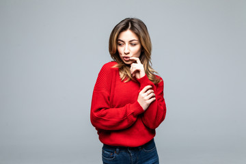 Young woman thinking an idea with red sweater over isolated on gray background © dianagrytsku