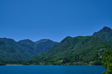 Fototapeta na wymiar Panoramic view of Lake Ledro in the north of Italy In the Alps. Blue lake, in the background green mountains, blue sky.