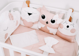 Fototapeta na wymiar Funny details of children room. Cushion-cloud, cat, hare. Sweet nursery room decorations for a baby girl. Stylish baby crib.