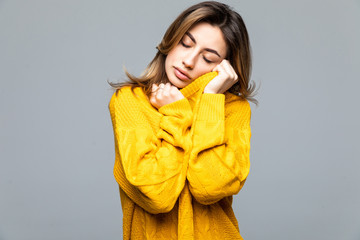 Young beautiful woman in yellow casual sweater standing with arms crossed isolated on gray...