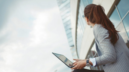 Young ambitious woman with a laptop in her hands on the background of the business center.
