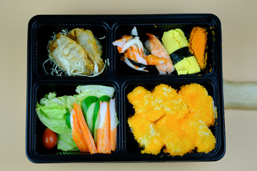 Fresh food portion in Japanese bento box with sushi rolls
